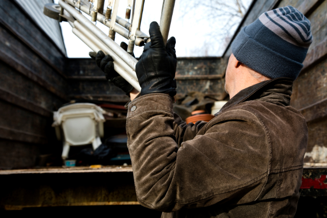 Junk Removal worker filling metal trash in bin